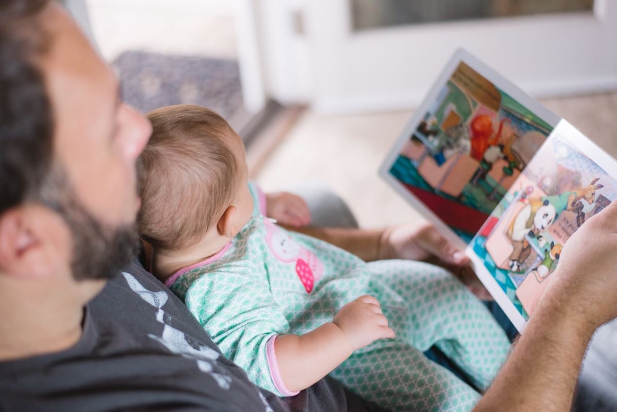 Man reading to a baby on his lap.
